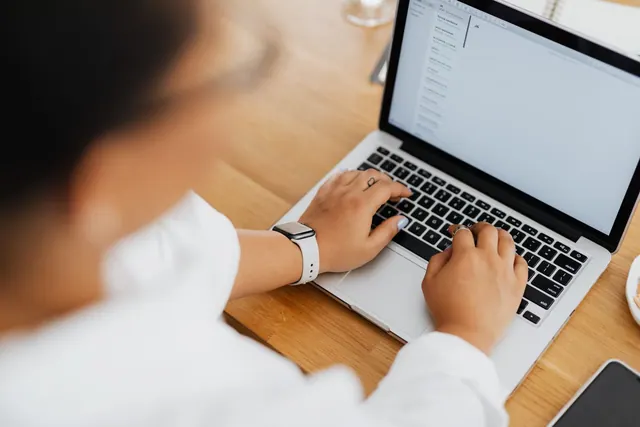 High angle shot of a person typing on a laptop, focused on hands and keyboard. Business email migration: how to switch without losing data